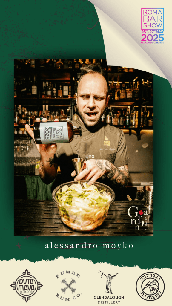 Alessandro Moyko, bar manager de I Giardini di Marzo, mentre prepara un cocktail in un bar, con una bottiglia in mano e un bicchiere con ingredienti freschi di fronte a lui. Sullo sfondo, una selezione di liquori e bottiglie. In alto a destra, il logo del Roma Bar Show 2025.